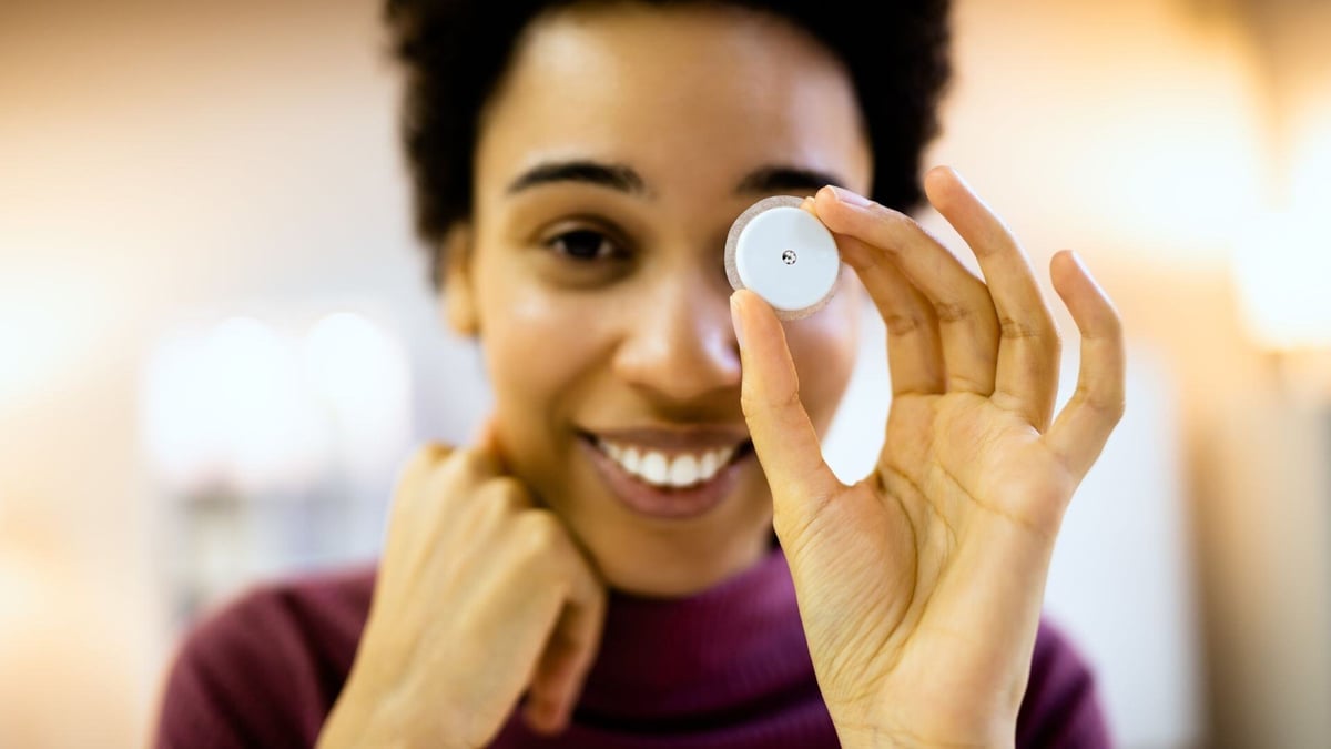 Medical-Wearables-woman-holding-cgm-sensor-in-front-of-eye